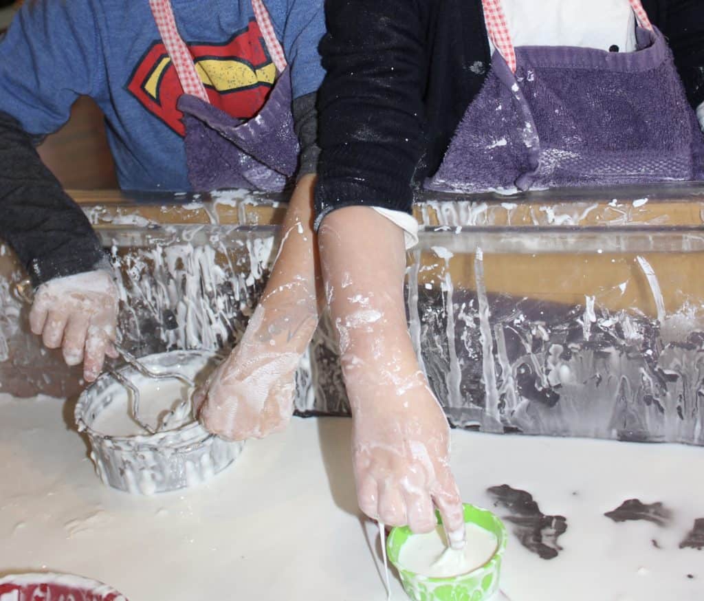 Two children's hands playing in a sensory table