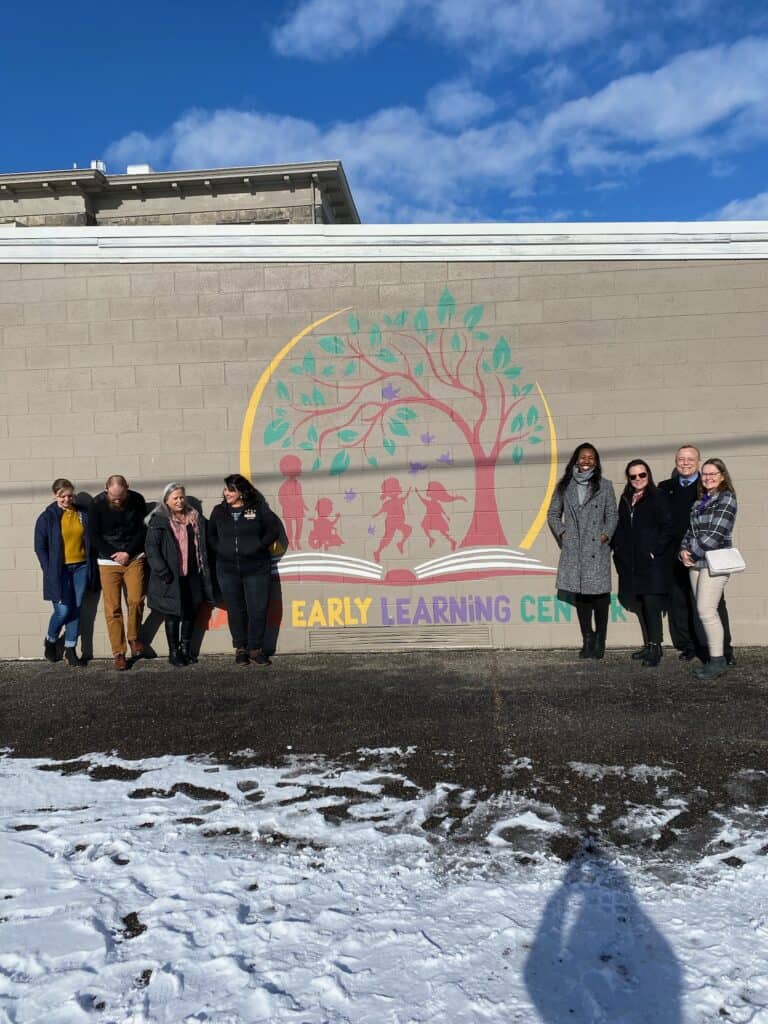Baker Early Learning Center and Children's Institute stand together in front of a mural at the Early Learning Center
