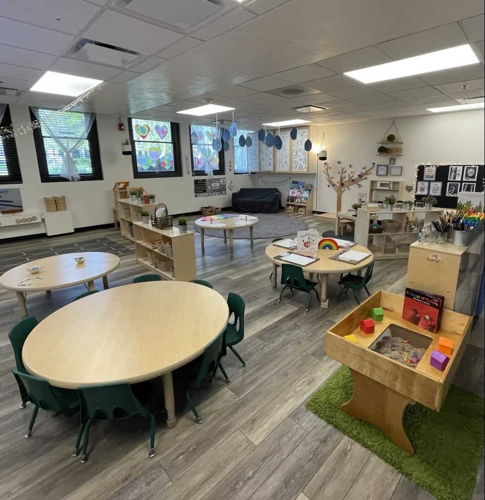This image shows a large preschool classroom with cute decorations and stations for different types of learning and play.