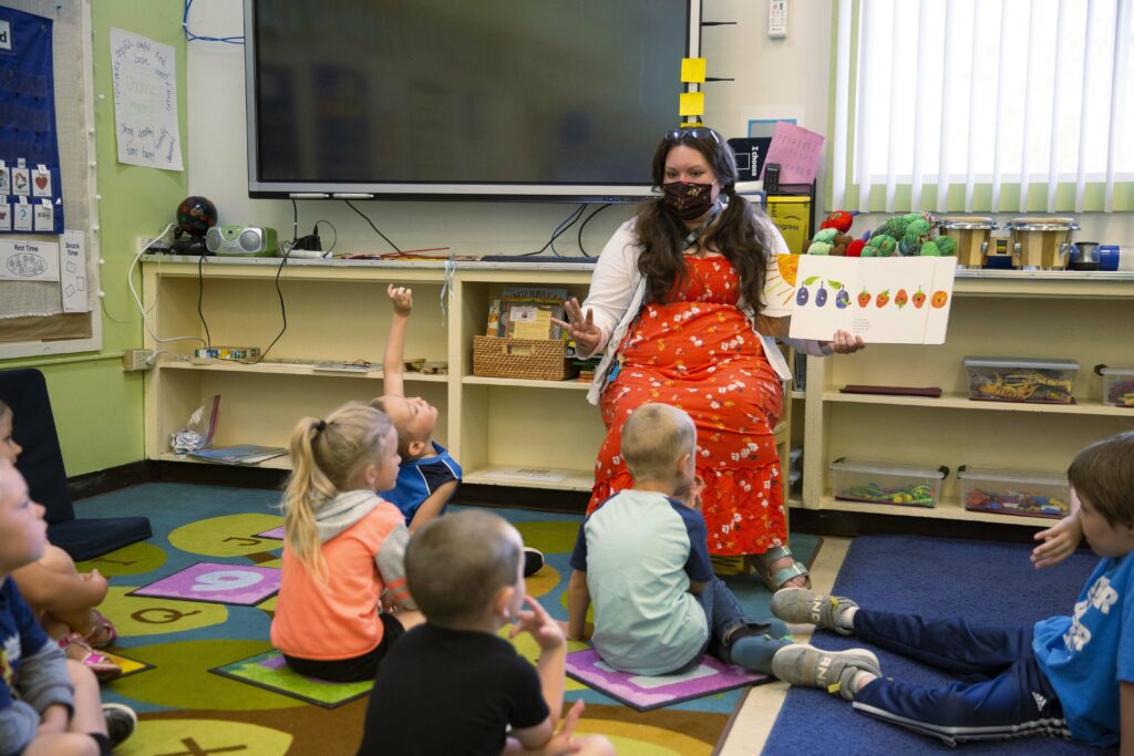 This image shows kids gathered around a teacher in a Yoncalla Preschool Classroom.