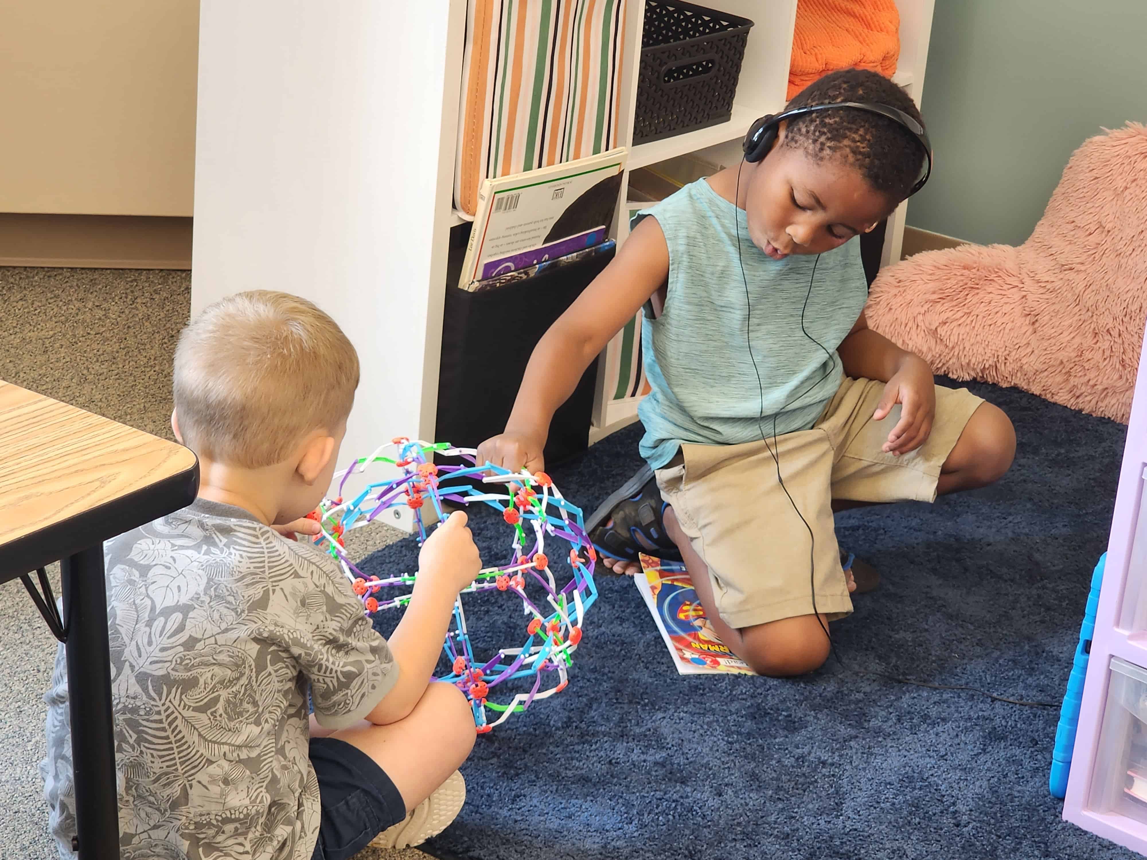 Two students play with a flexible sphere in a classroom setting at Kinder Camp.
